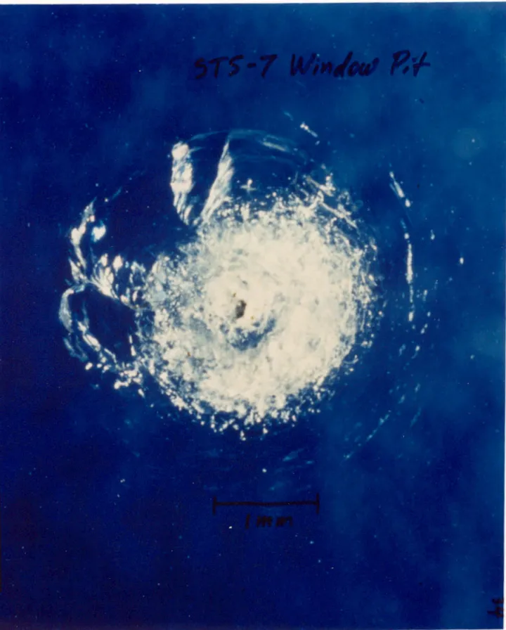 1983年STS-7任务后，挑战者号舷窗上的撞击坑。NASA资料将撞击物识别为微小油漆碎片。